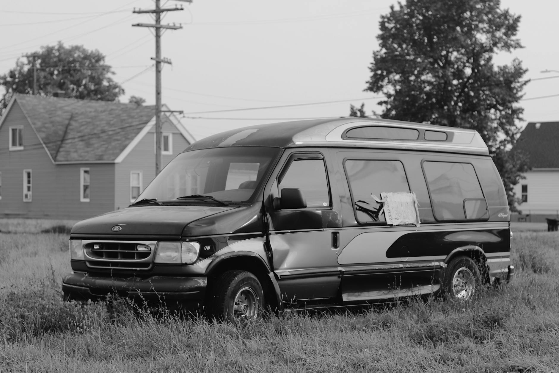 A black and white photo of a van parked in a field