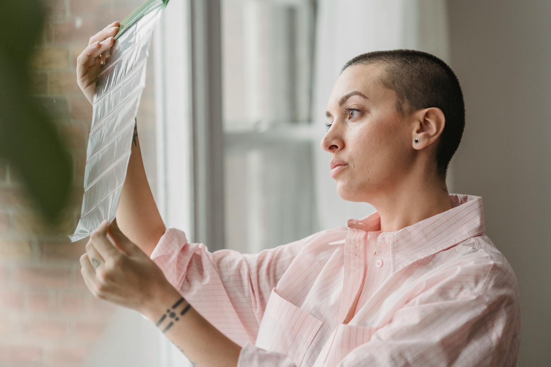 Confident young female photographer watching film tapes near window