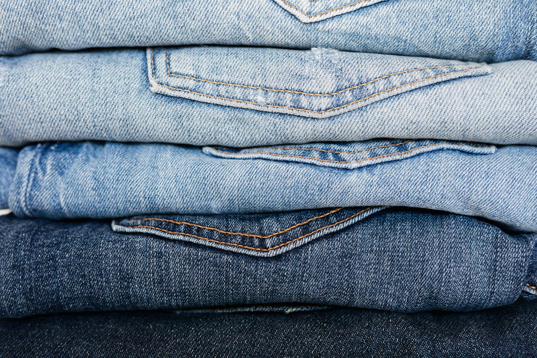 Closeup of stack of blue denim pants neatly arranged according to color from lightest to darkest