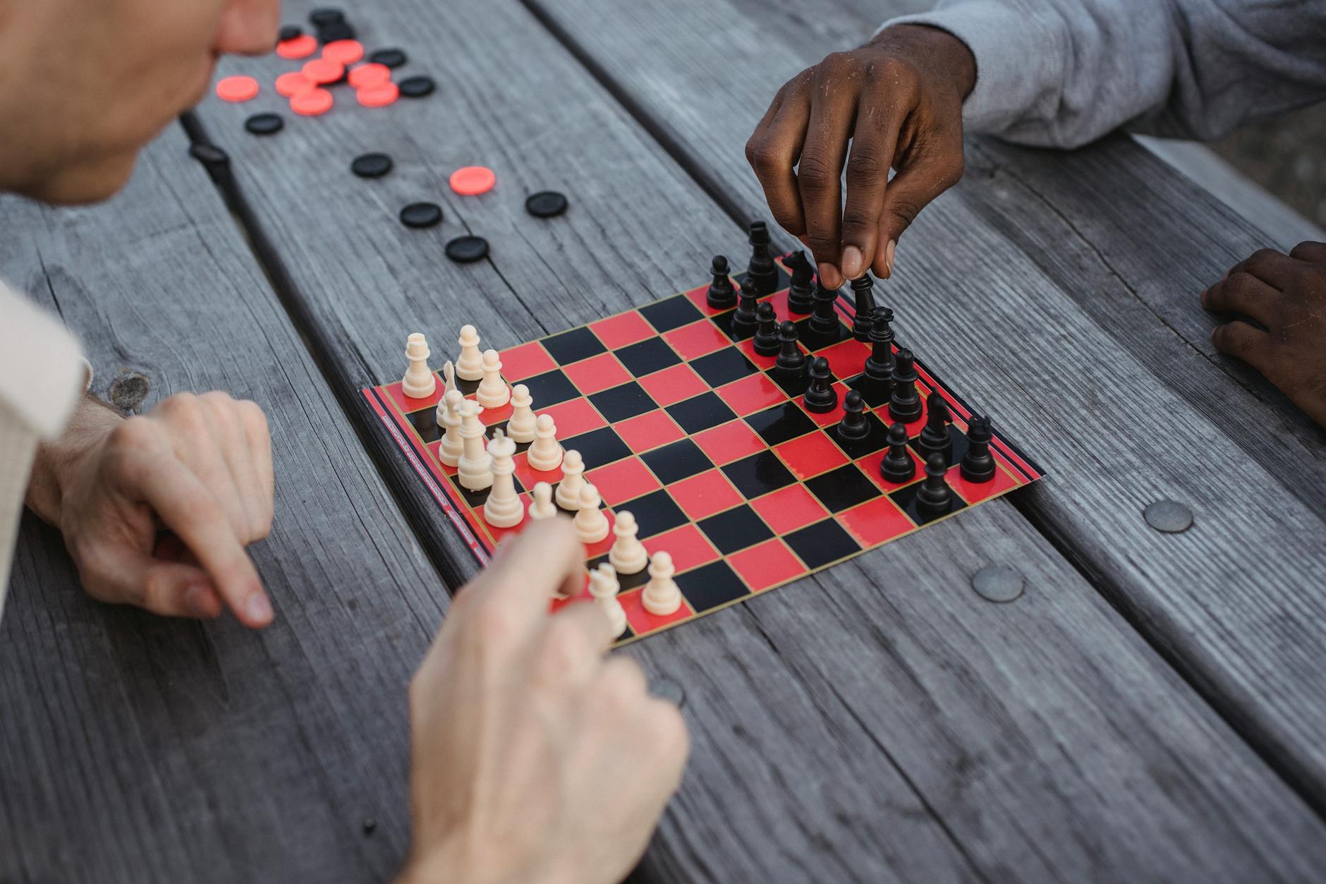 Unrecognizable multiracial male millennials playing chess at wooden table