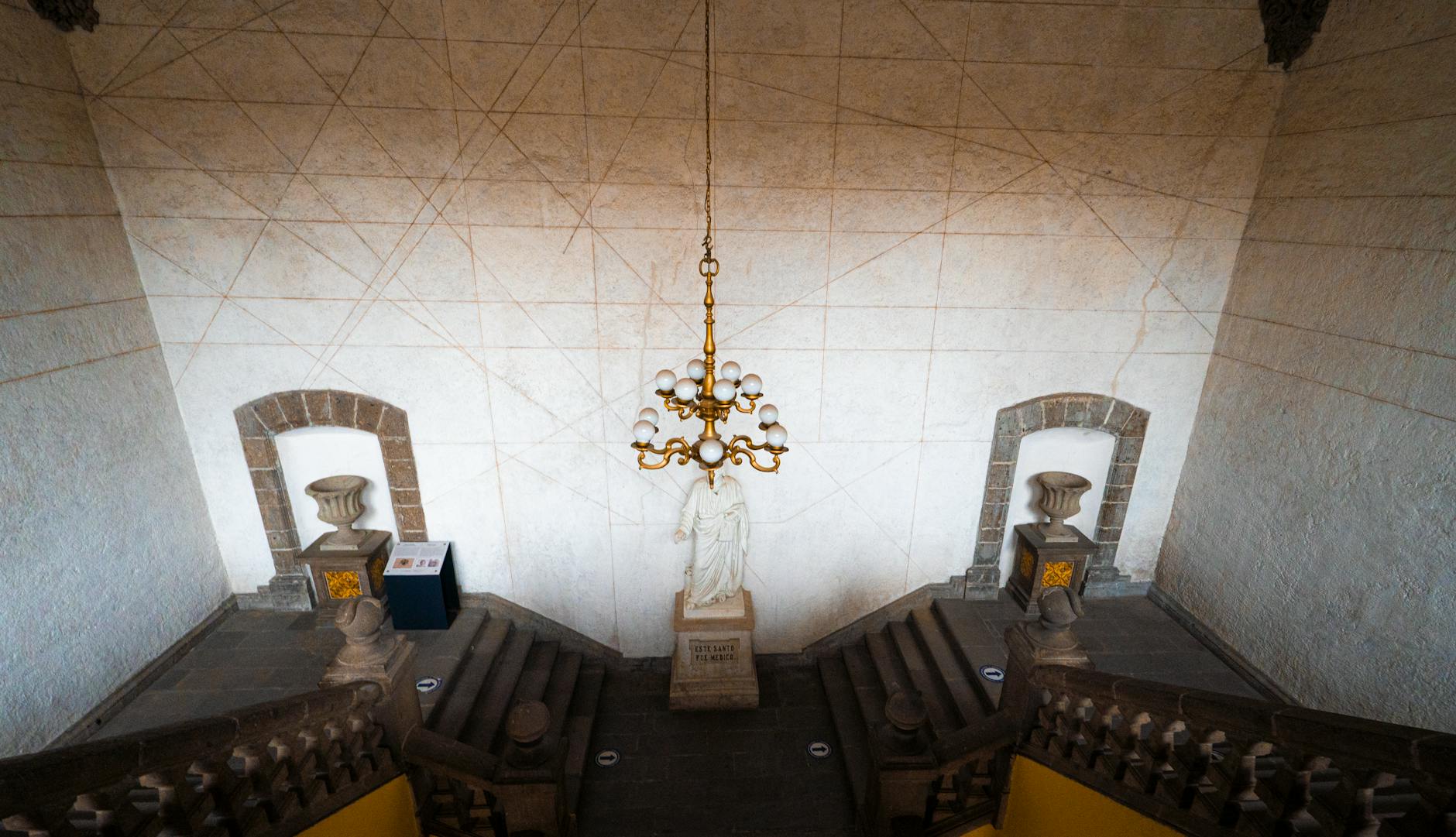 A view of a staircase with a chandelier and a clock