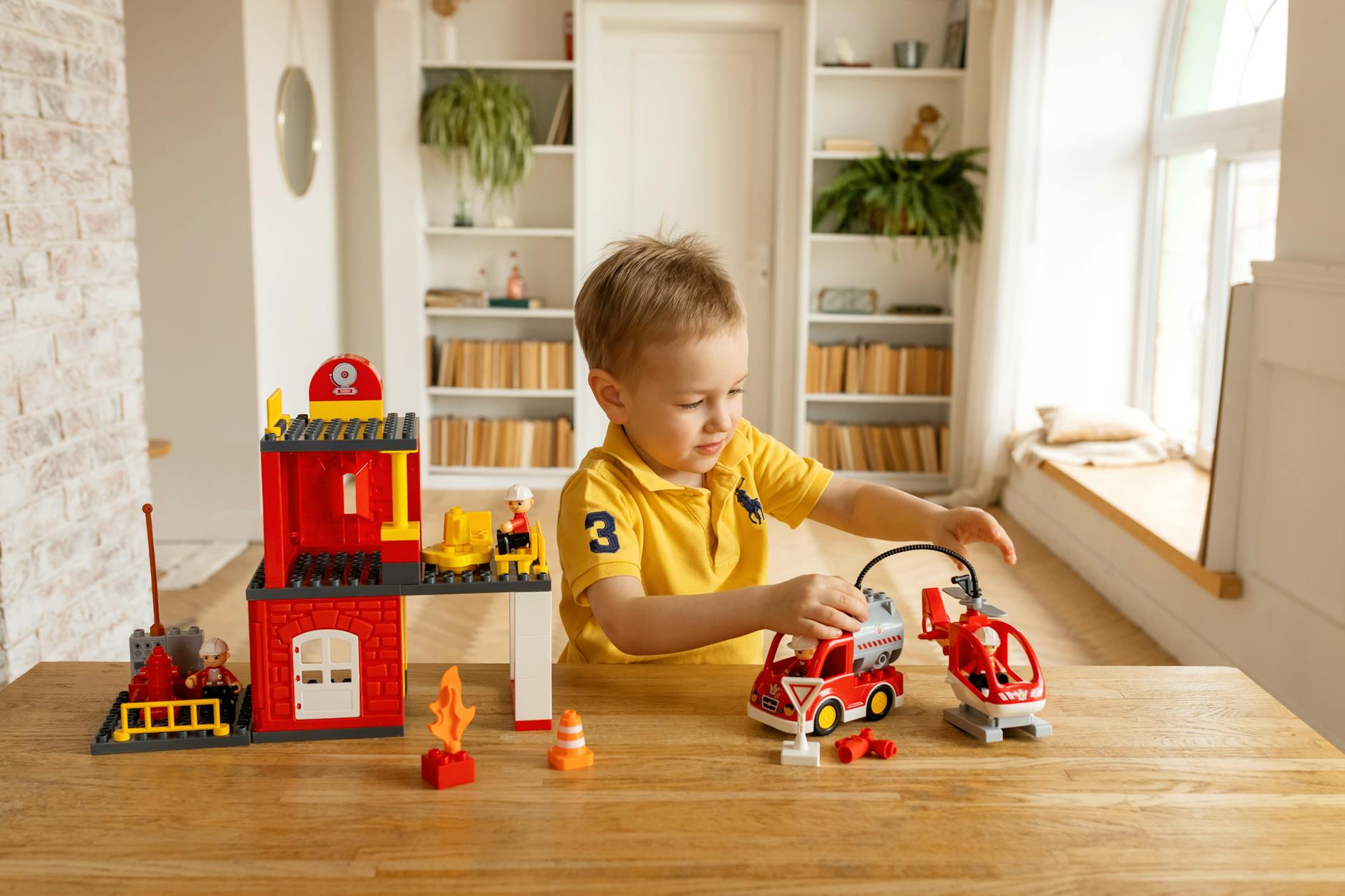 Boy Playing with a Toy Car and a Helicopter from a Set of Blocks