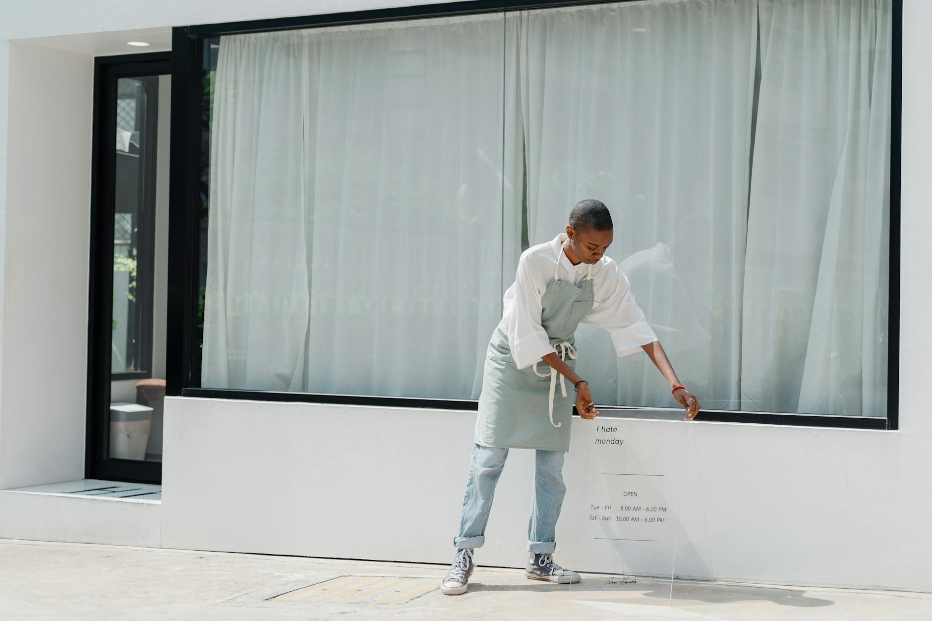 Diligent black female worker setting signboard outside cafeteria at sunny day