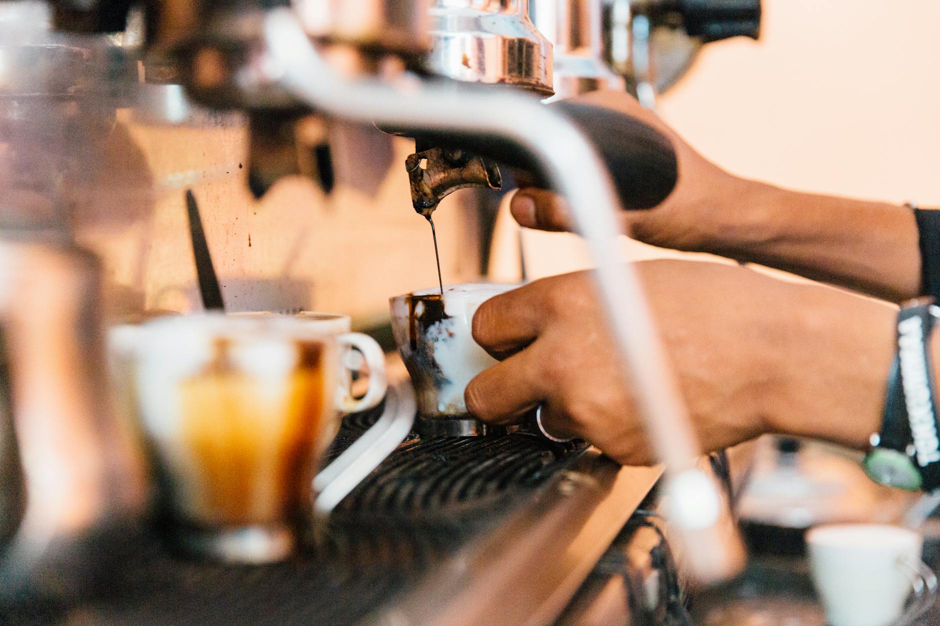 Faceless employee pouring coffee from machine in cafeteria