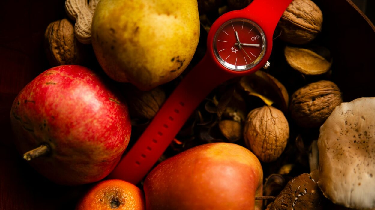 From above of red rubber wristwatch placed in healthy basket with organic fresh apples pear and orange and composed with different nuts