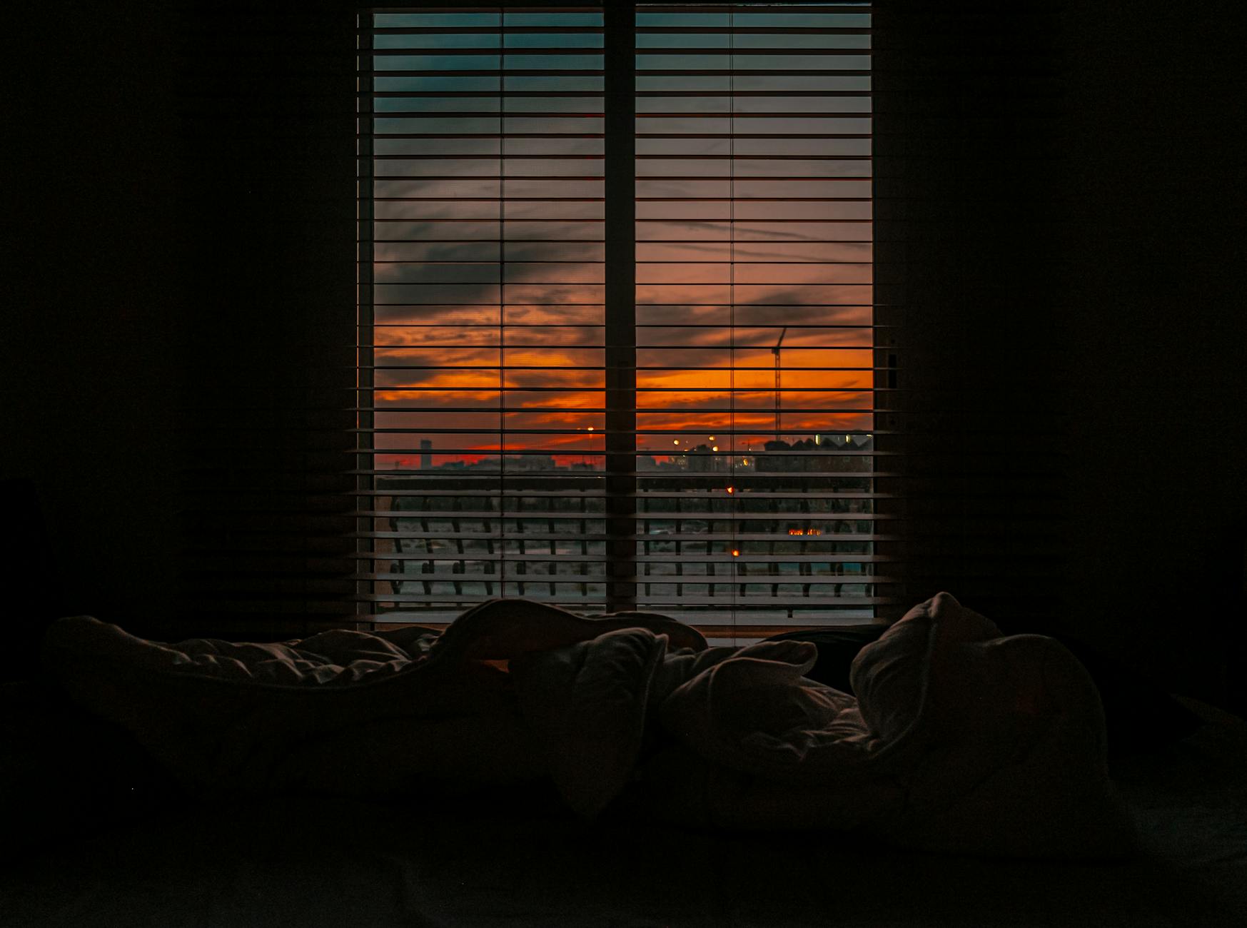 Crumpled blanket in dark room at sunset