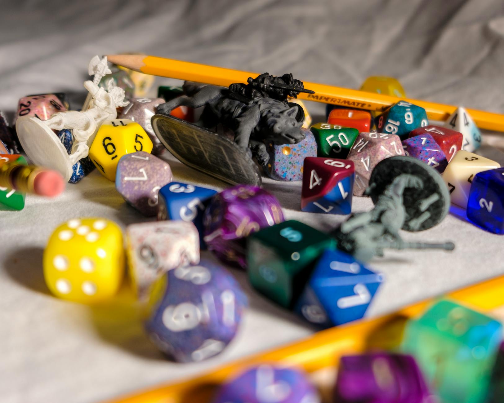 High angle of color dices in different shapes scattered on table with small toy animals and pencils during game