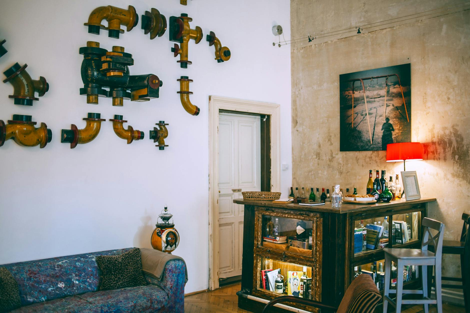 Comfortable retro styled room with metal pipes on wall near vintage table with various glass bottles